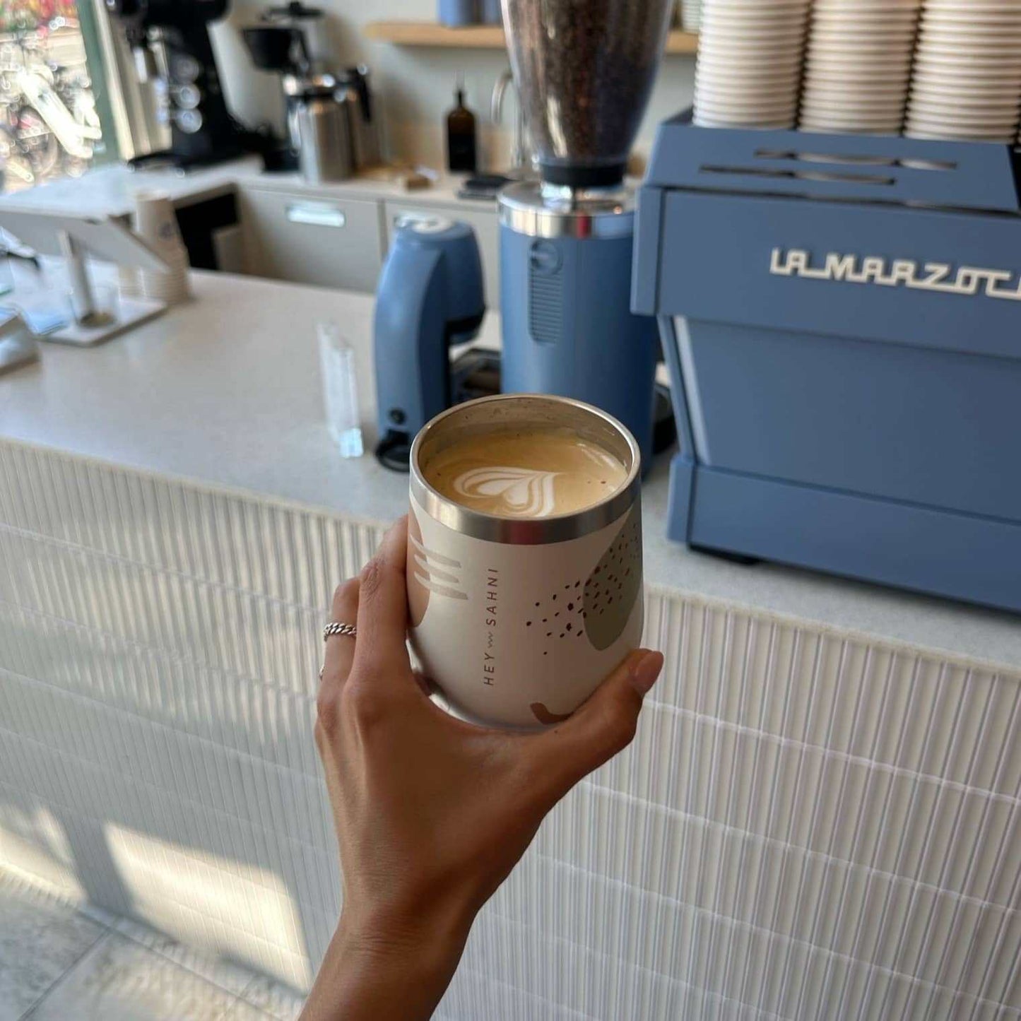 Stainless steel cup with coffee in a cafe setting.