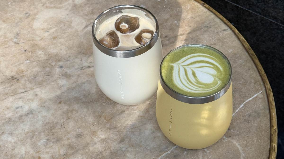 Two HEY SAHNI stainless steel cups with iced matcha lattes on a marble table