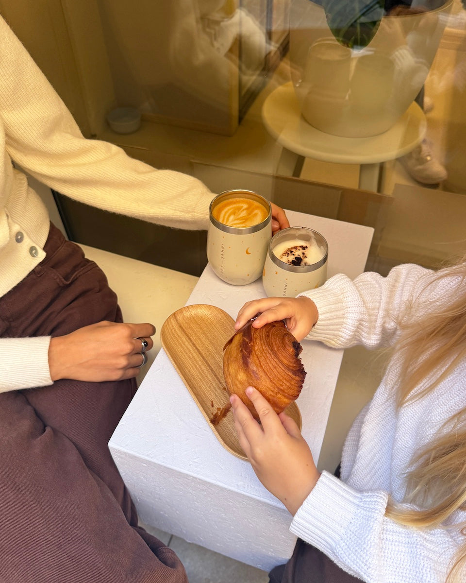 Two people sitting at a table with a wooden plate and a cup of coffee.